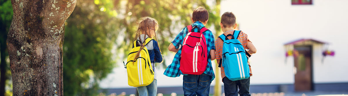 three kids wearing backpacks walking