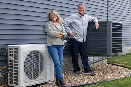 Pete and Megan standing next to an air conditioner