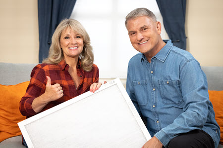 Pete and Megan from Alliant Energy's PowerHouse holding a furnace filter