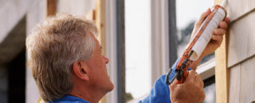 Man caulking around window