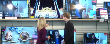 Megan and TV salesperson in front of a wall of TVs