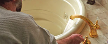 man turning on a faucet on a whirlpool tub